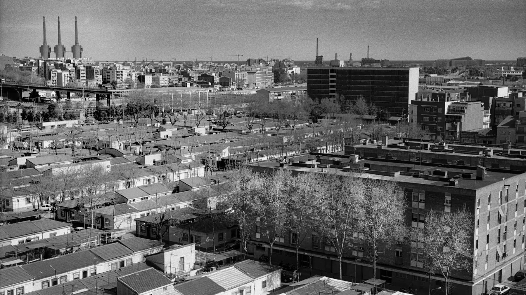 Rows of low cases barates in Bon Pastor seen from above, apartment blocks and industrial chimneys behind