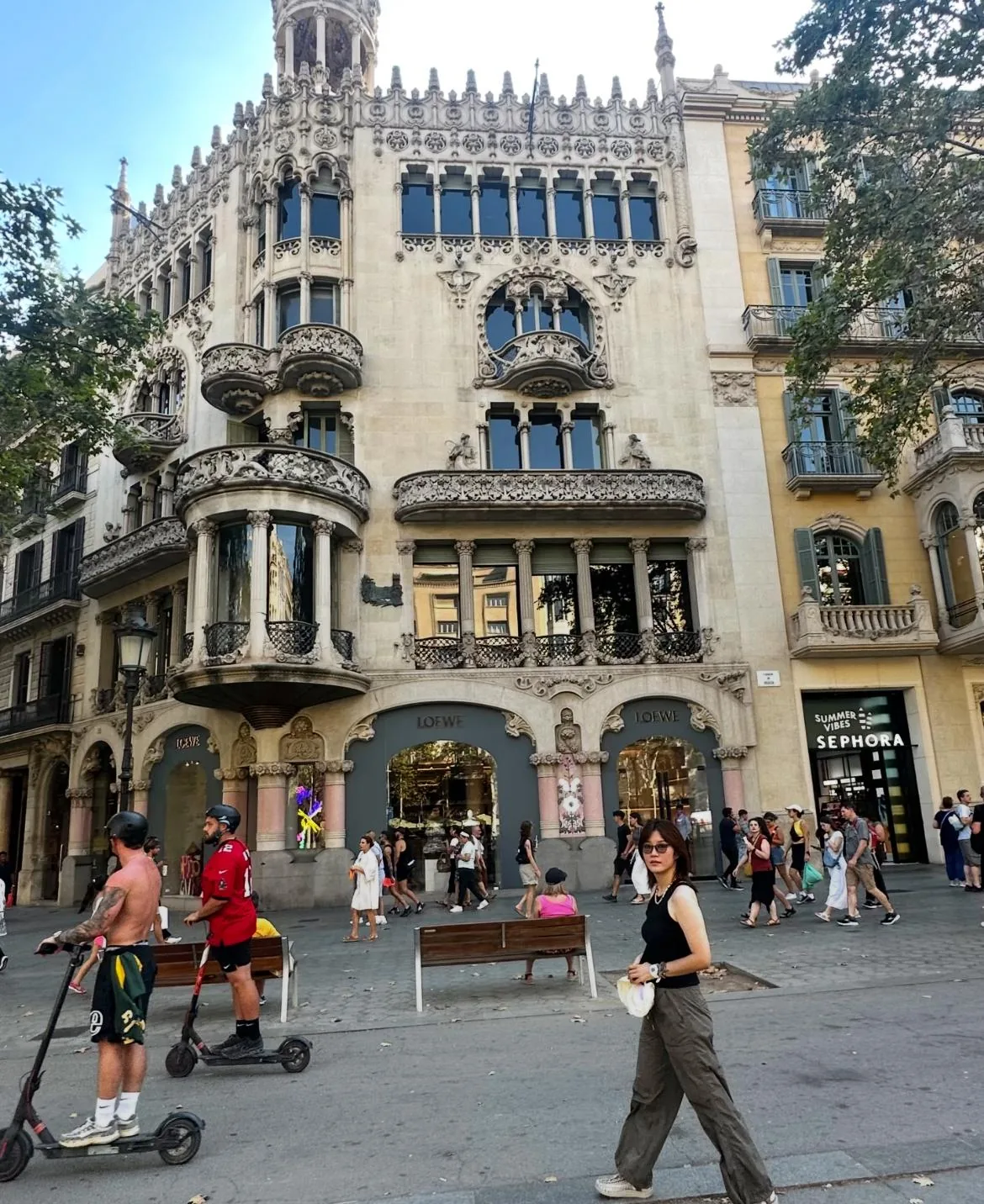 A chamfered Eixample corner: pedestrians and e-scooters in front of a Modernista building